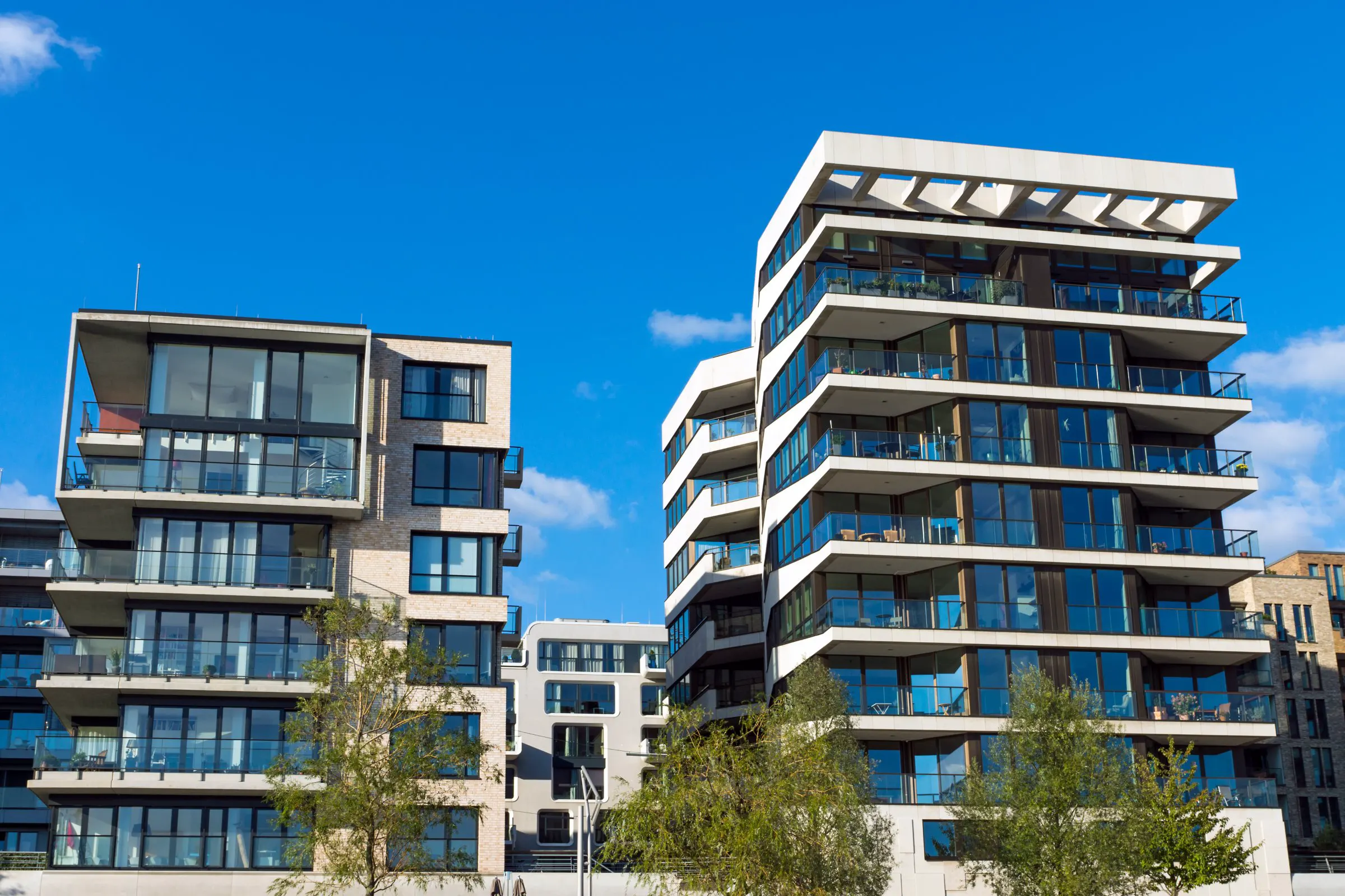 Mehrgeschossige moderne Wohngebäude mit Balkonen vor blauem Himmel.