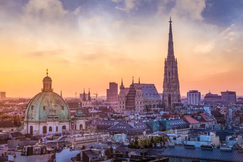 Historische Dächer und ein Kirchturm in Wien im Abendlicht