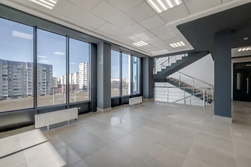 Leere Bürofläche mit großen Fenstern und offener Treppe